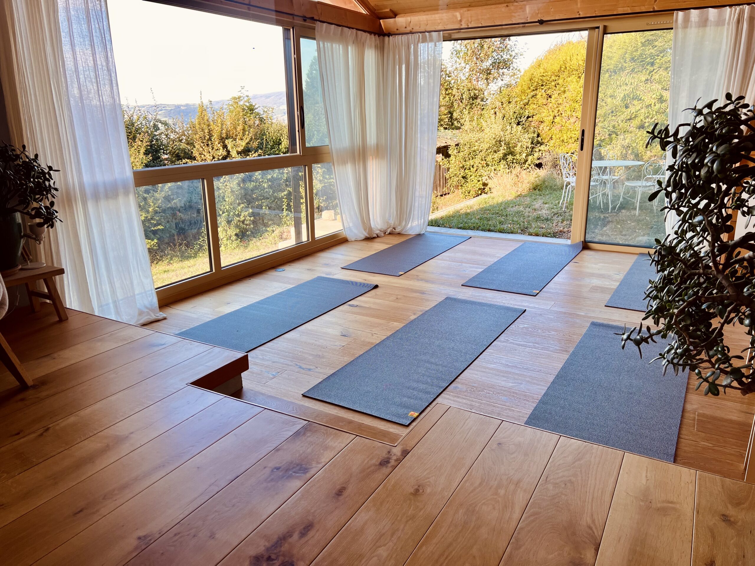 Accueil salle de yoga doux au Sanctuaire à Fillinges, avec tapis installés face aux grandes baies vitrées donnant sur la végétation